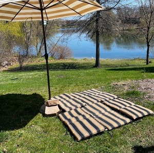 lot 24 image: Tan and White Striped Tiltable Umbrella with stand and 6 Tan and Black Striped Patio Chair Cushions