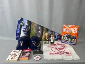 lot 42 image: MN Twins Memorabilia - Sid Hartman Bobblehead, Catt Bobblehead, Pennant Flag, 2 Plastic Promo Helmets, Kent Hrbek Statue, 2 2002 Homer Hankies, 1987 Champions Pin and 1987 Champion Wheaties Box
