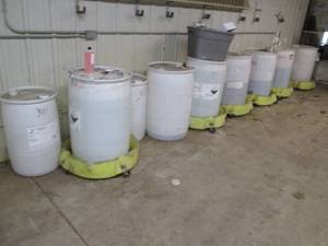 lot 148 image: Large lot of 55-gallon and 33-gallon drums with assorted liquids PLUS 6-tank scooters