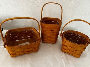 lot 4 image: Set Of Three Longaberger  Baskets With Handles. Square Measuring 7 Inches Wide By 4 Inches Tall, 5 12 Inches Wide By 6 Inches Tall, And The Round Is 5 12 Inches Diameter By 4 12 Inches Tall