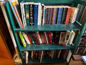lot 34 image: Green Folding Bookcase And All The Books Included Measuring 30 Inches Wide By 12 Inches Deep By 36 Inches Tall