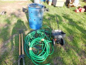 lot 11 image: Blue Barrel with three garden hoses post hole digger and broadcast spreader