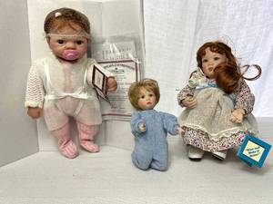 lot 16 image: Ashton-Drake Porcelain Dolls Kiss and Make It Better Family Ties Collection by Mary Tretter and Celebration of Life Emmy by Linda Webb