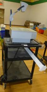 lot G111 image: Audio visual cart with an overhead projector, a projector screen and a samsung monitor