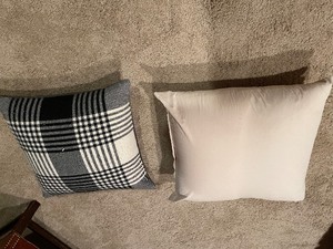 lot 209 image: Two Large Overstuffed Pillows Measuring 21 x 21 Inches And 19 x 19 Inches. Larger Pillow, Off-White Color, Slightly Smaller Pillow With Black And White Pattern On One Side, Gray Herringbone On The Other Side.