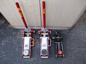 lot 162 image: (2) red Teq Car 11.5-ton floor Jacks. (1) black Car Floor Jack with 2 red handles. (Black jack doesnt have a handle)