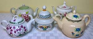 lot 23 image: Set of 5 Teapots - Royal Albert Rose Garden, Villeroy & Boch 1748 Germany Basket Teapot,  Portmeirion The Botanic Garden Teapot, Porcelain Rose Gold Trimmed Unbranded Teapot, and Tricia Handmade Floral Pot