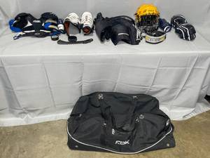 lot 190 image: Set of Used Junior SZ M Hockey Gear Inc Helmet, Breezers, Shoulder Pads, Shin, Elbow, Neck Guards & Gloves in Reebok Black Roller Bag