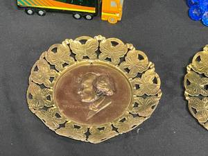 lot 201 image: 2 Avon Empty Cologne Bottles Trucks, MCM Punch Bowl Glasses Culver Briard Style Gold Finish, VTG Brass Bear Bell, VTG Hummel Music Box, VTG Lucite Glass Grapes from Taiwan, Brass Wall Hangings BeethovenTchaikovskyMendelssohn, Vase with Gold Trim