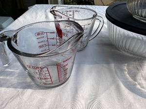 lot 142 image: Pyrex Covered Mixing Bowls and Two Glass Measuring Cups