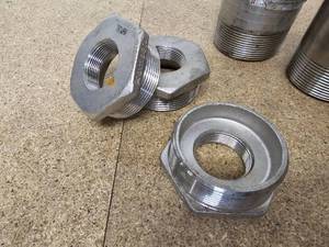 lot 68 image: Looks to be stainless steel hex reducing bushings, Polymate grooved adapters 3x2 15 and 3x3 threaded pipe nipples