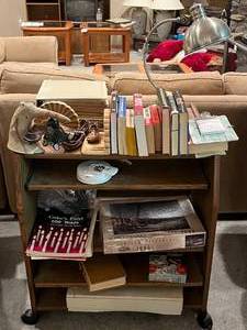 lot 488 image: BASEMENT - Assorted Books, Collectibles, and Rolling Wooden Shelf Lot