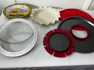 lot 93 image: Pie Making Supplies, Including A Ruffled Edged Pie Plate, Glass Pie Plate, Pie Weight, Drip Protector, Piecrust Protector, And Piecrust Cut Out