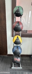 lot 73 image: (5) Weighted exercise balls with rack.  (4 Nike 4lb, 6lb, 8lb & maybe 10 lb- one SPRI 18 lb two handles