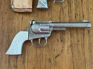 lot 104 image: Vintage Toy Western Cowboy Holster with Hubley Toy Rodeo Star Cap Gun, Hubley Toy Star Cap Gun, and Kit Carson Toy Cap Guns