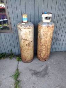 lot 390 image: 2 tanks  cylinders approx 5 foot High, One has a Tulip Cap and one has a collar