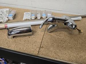 lot 31 image: Variety of bathroom plumbing items - single handle faucet, tub spout, 2 shower curtain rods, 11 Moen single-handle tubshower replacement cartridges (6 - 1222B and 5 - 1225)