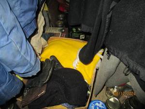 lot 369 image: Contents of closet under the stairs. Visible items include a Panasonic tube television, canning jars, winter coats and more