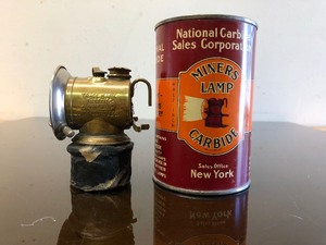 lot 193 image: Antique Brass JUSTRITE Miners Lamp & NOS Carbide Advertising Can wGreat Graphics