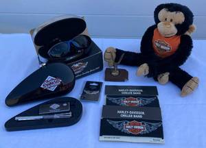 lot 17 image: Harley Davidson Goggles, Chiller Bands, White Wings Pin, Monkey, Waterman Writing Instrument, Eagle Hood Ornament and Belt Buckle