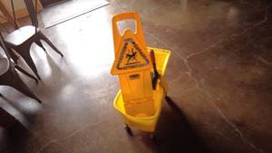 lot 142 image: Yellow Mop Bucket with Wringer and Caution Sign