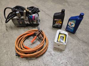 lot 9 image: Portable PowerPal air compressor, jumper cables, 2 quarts of motor oil (Mag 1 is open and about 75% full) and one John Deer T19044 oil filter for tractors