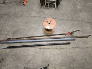 lot 41 image: partial spool of electrical wire, pole saw, 11 pole for electrical work, and some PVC conduit tubes