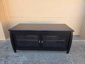 lot 30 image: Stylish Black Wooden TV Stand with Glass Doors and Storage Space