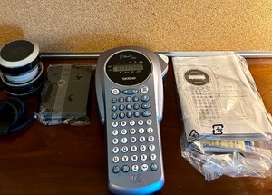 lot 67 image: Variety of Office Supplies Including a Handheld Brother Label Maker and Ribbon, IHome and Bulletin Board with Pins