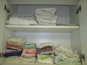 lot 43 image: Cupboard filled with cloths and tow...
