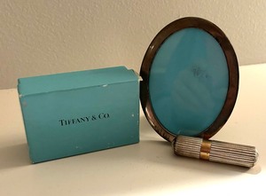 lot 99 image: Tiffany & Co Miniature Brass Oval Frame and Lipstick Cover
