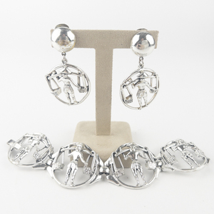 lot 208 image: Selini  Balance The Yoke Motif Silver Tone Base Metal Bracelet & Clip-On Earrings.
