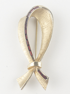 lot 233 image: Stylized Bow With Deep Red Rhinestone Set Channel Yellow Base Metal Brooch .