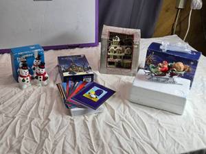 lot 46 image: Assorted Holiday Decor Including Snowman Set, Christmas Cards, Lighted Village House, and Santa Sleigh