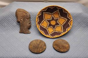 lot 8 image: African Art Collection Two Carved Wooden Faces and Handwoven Decorative Basket with Coasters