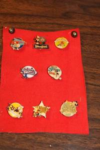 lot 141 image: Collection of 8 Vintage Disneyland Pins on Red Fabric Display