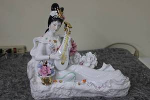 lot 103 image: Elegant Porcelain Figurine of Woman Playing Lute with Floral Accents
