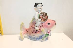 lot 1119 image: Porcelain Figurine of Child Riding a Pink Fish with Gold Accents