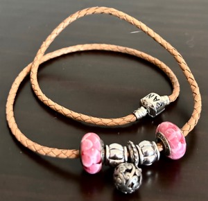 lot 384 image: Pandora Brown Braided Leather Necklace with Five Pendants in Pink, White and Silver