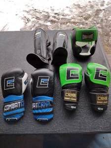 lot 157 image: Combat CRNR S-Class (blue) gloves, 12 oz green gloves, MMA spar shin guards, and CNCR Full-face head gear
