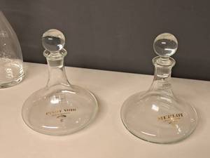 lot 994 image: Lot of (2) 9-12 Clear Glass Round Wine Decanters with Topper - Merlot, Pinot Noir
