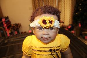 lot 139 image: Realistic Baby Doll with Yellow Dress and Sunflower Headband
