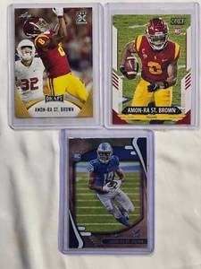 lot 129 image: Lot of 3 Amon-Ra St. Brown Rookie Cards - 2021 Leaf Draft No. 27, Panini Score No. 330, Panini Absolute No. 131