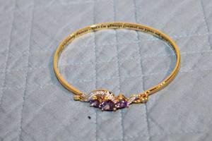 lot 36 image: Elegant Gold Bangle with Purple Gemstone Accents