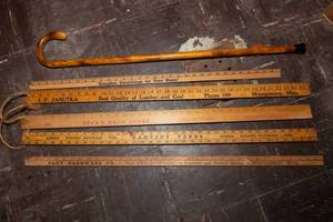 lot 407 image: Vintage Yardsticks of Montgomery, MN Businesses and a Wooden Cane
