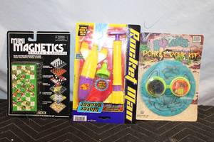 lot 392 image: Set of 3 Pocket Games Snakes & Ladders, Rocket Man Water Rocket, and Pogs Rokk Kit