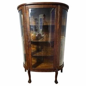 lot 6 image: Johnny Cash Owned  Antique Quarter Sewn Oak Curved Glass Curio Cabinet with Claw Feet $3,000 - $6,000 Estimate