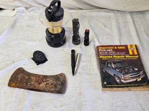 lot 48 image: Axe Head, Battery Lantern, Faux 50 Cal Bullets, Flashlights and Haynes Chevrolet & GMC Repair Manual