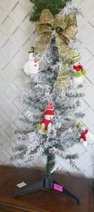 Flocked christmas tree decorated with snowmen and a bow