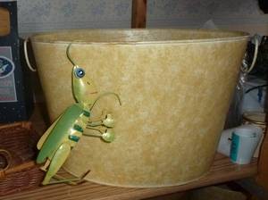 large metal basket planter with a grasshopper hanging on the side